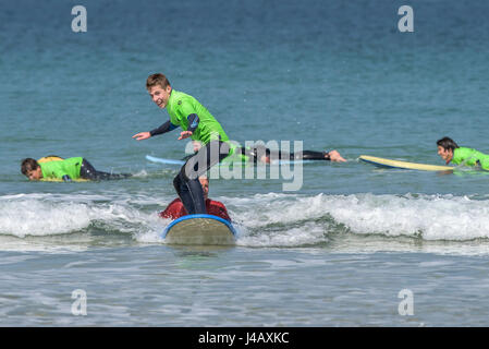 Ein Surf-Schule-Neuling surft zum ersten Mal Fistral Strand Newquay Cornwall Surfen Surfer Lerner lernen am Meer Meer Tourismus Stockfoto