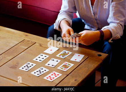 Frau bei Solitaire Kartenspiel auf einem niedrigen Holztisch Stockfoto