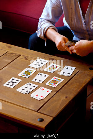 Frau bei Solitaire Kartenspiel auf einem niedrigen Holztisch Stockfoto