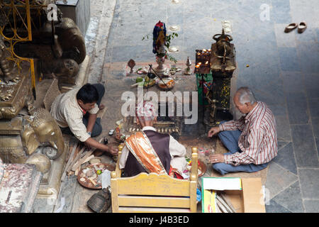 Drei Männer und Opfergaben und Gebete für Buddhas Geburtstag in den goldenen Tempel - Hiranyavarna Mahavihara - Patan, oder Lalitpur, Kathmandu, Nepal Stockfoto