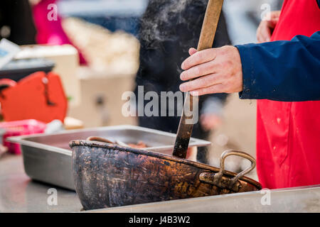 Outdoor-Küche mit einem Mann im Sommer in einem heißen Topf mit Rauch um rühren Stockfoto