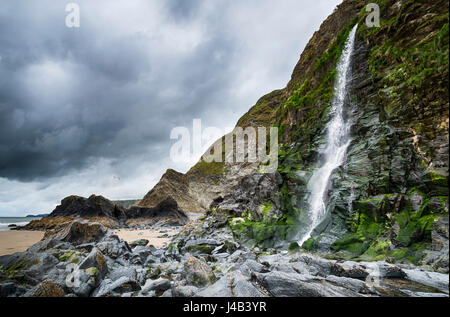 Wasserfall des Flusses spricht fließt über Klippen am Strand an der Tresaith Bucht, einem Küstendorf in Ceredigion, Wales. Stockfoto