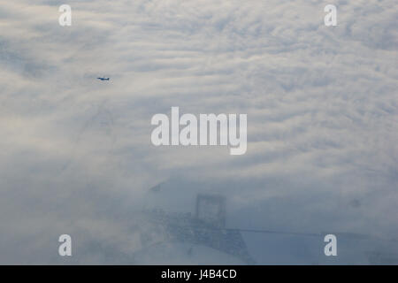 München, Deutschland - 21. Januar 2017: Flugzeug fliegt in weißen Wolken in einem blauen Himmel und hinterlassen Spuren, von einem anderen Flugzeug aus gesehen Stockfoto