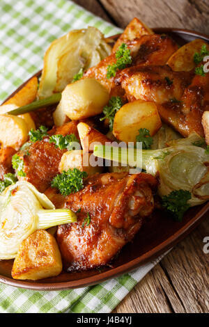 Stücke vom Huhn gebacken mit Fenchel und Kartoffeln Nahaufnahme auf einer Platte. Vertikal Stockfoto