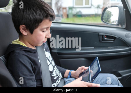 Junge, 10 Jahre alt, spielt Computerspiel in Auto, UK Stockfoto