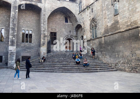 Menschen sitzen die Treppe zu den Saló del Tinell und die Kapelle St. Agatha am Placa del Rei, Barcelona, Spanien. Stockfoto