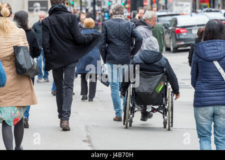 Behinderte Menschen im Rollstuhl an einer befahrenen Straße unter Schar von Menschen Stockfoto