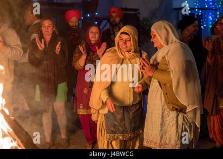 Punjabi Frauen bereiten, Samen in das Lohri Feuer zu werfen. Es ist Tradition, kleine Gegenstände in die Lagerfeuer, Respekt, Feuer und Natu werfen Stockfoto