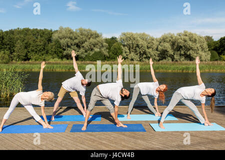 Menschen, die Yoga im linken Dreieck-Pose im freien Stockfoto