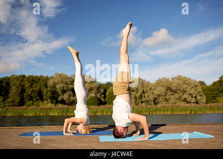 paar macht Yoga Kopfstand auf Matte im freien Stockfoto