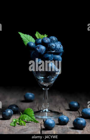 Heidelbeeren mit Blättern in kleinen Glas Stockfoto