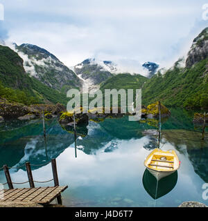 Angelboot/Fischerboot auf einem noch See in Norwegen und hohen Bergen im Hintergrund. Bondhusvatnet Stockfoto