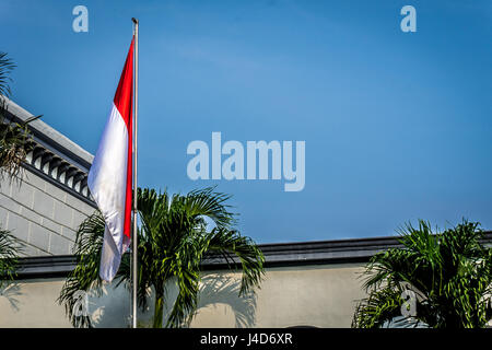 Indonesien-Flagge am Mast mit Gebäude als Hintergrund Stockfoto
