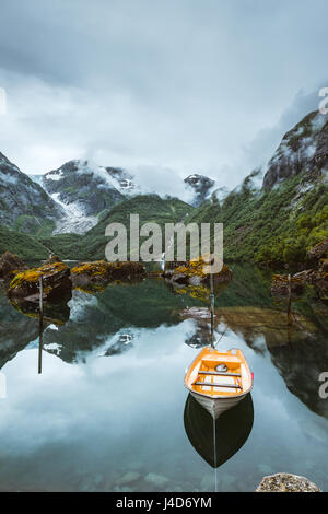 Angelboot/Fischerboot auf einem noch See in Norwegen und hohen Bergen im Hintergrund. Bondhusvatnet Stockfoto