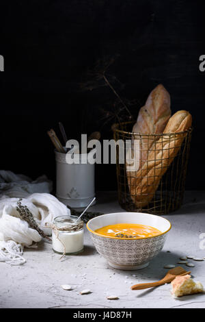 Scharfes Curry Creme Suppe am Tisch mit gebackenem Brot und Sauerrahm. Gesunde vegetarische Ernährung. Stockfoto