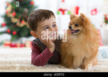 Wenig Kind Junge mit Hund auf dem Boden liegend in Festsaal Stockfoto