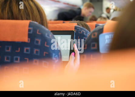 Person lesen Ebook auf Flugzeug Flug Stockfoto