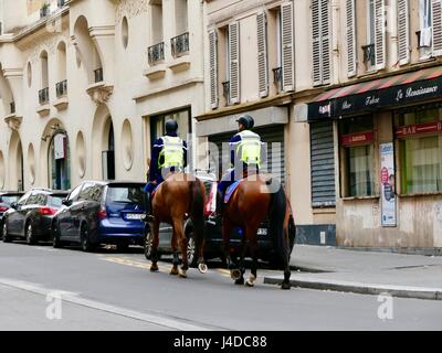 Zwei Gendarmen, bewaffnete Polizei, reiten Pferde die Straße hinauf auf Patrouille, rue de Championnet, 18. Arrondissement, Paris, Frankreich. Mai 2017 Stockfoto