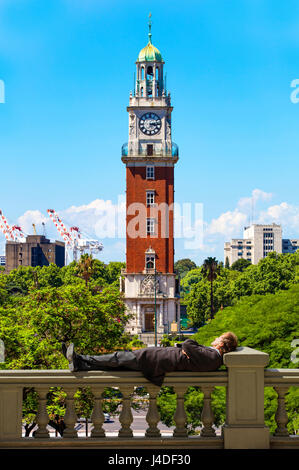 Ein Mann in Anzug entspannen in Plaza San Martin mit dem Turm der Engländer im Hintergrund. Retiro, Buenos Aires, Argentinien. Stockfoto