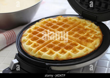 hausgemachte Waffeln vorbereiten von Waffle Maker Maschine. Stockfoto