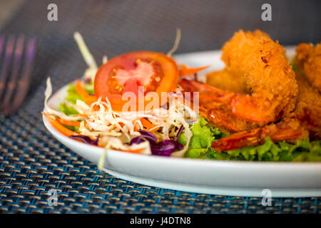 Große Garnelen in Teig mit Gemüse auf einem Teller hautnah Stockfoto