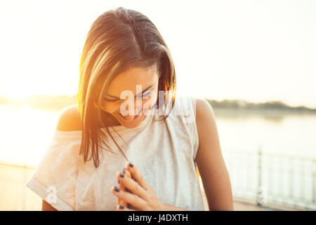 Lächelnde Jogger Frau am See bei Sonnenuntergang. Sport- und Lifestyle-Konzept Stockfoto