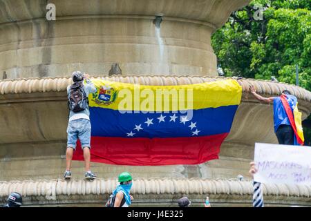 Junge Leute legen Sie eine Flagge Venezuelas in der Obelisk von Frankreich Platz des Altamira.Under dem Motto "Unser Schild ist die Verfassung", oder auch genannt den "Marsch der Schilde", Demonstranten begann sich in den verschiedenen Teilen der Stadt, Supreme Court of Justice (TSJ) zu erreichen. Caracas, 10. Mai 2017 Stockfoto