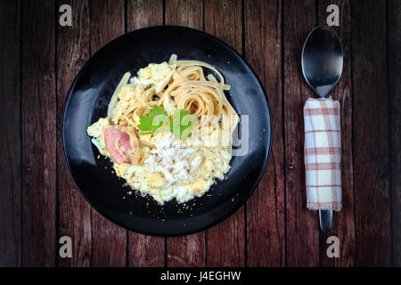 Spaghetti Carbonara-Rezept mit Krabben in schwarzer Schale. Stockfoto