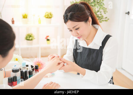 schöne asiatische chinesische Berufsfrauen Maniküre Überprüfung Nagel Pflege ihrer Kunden bereit zu tun, das Spa Beauty-Salon. Stockfoto