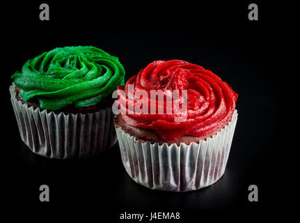 Zwei Muffins, rot und grün auf schwarzem Hintergrund isoliert Stockfoto