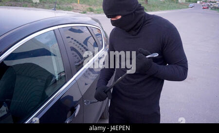 Räuber mit einem Brecheisen in der Nähe von der Autotür. Stockfoto