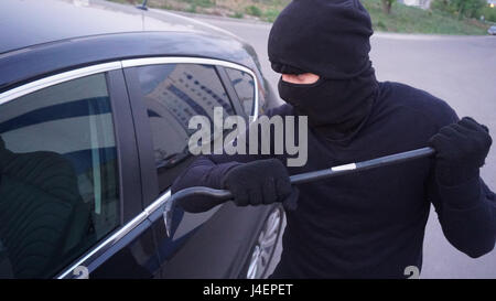 Räuber mit einem Brecheisen in der Nähe von der Autotür. Stockfoto