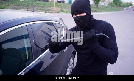 Räuber mit einem Brecheisen in der Nähe von der Autotür. Stockfoto