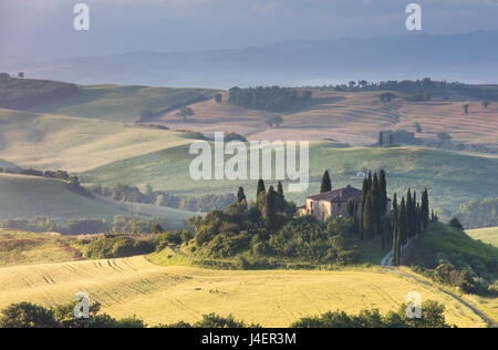 Sonnenaufgang auf den sanften grünen Hügeln und typisches Bauernhaus des Val d ' Orcia, UNESCO, Provinz Siena, Toskana, Italien Stockfoto