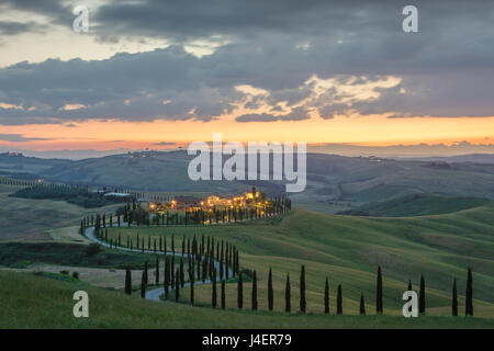 Sonnenuntergang auf grünen Hügeln, umgeben von Zypressen und Bauernhäuser, Crete Senesi (Senese Tonen), Provinz Siena, Toskana, Italien Stockfoto