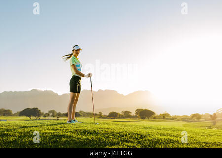 Volle Länge des kaukasischen Golfspielerin am Golfplatz. Frau, spielen Golf auf Feld an einem sonnigen Tag. Stockfoto