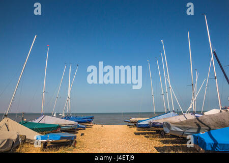 Kleine Segelboote aufgereiht am Meer auf dem Sand in Whitstable, Kent, Großbritannien Stockfoto