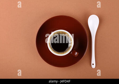 Volle kleine braune Keramik Espressotasse schwarzen Kaffee mit Untertasse und weißen Löffel auf Papier, Pergament, Nahaufnahme, erhöhte Ansicht von oben, direkt über Stockfoto