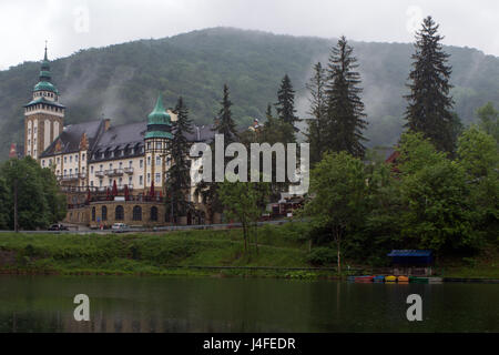 Das Palace Hotel und der Hamori See in den Bukk Bergen in Lillafared, Miskolc, Ungarn an einem regnerischen Tag. Bunte Boote auf dem See. Stockfoto