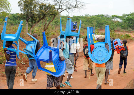 ANGOLA Kwanza Sul, Dorf Kassombo, Kinder auf dem Weg zur Schule, jedes Kind seinen eigenen Stuhl aus Kunststoff wie die Schulen in schlechtem Zustand durch den Bürgerkrieg und Korruption bringen muss, die Einnahmen aus Öl reichen Angola scheint nicht erreichen die Dörfer / ANGOLA Kwanza Sul, Dorf Kassombo, Kinder Mit Plastikstuehlen Auf Dem Weg Zur Schule Durch Felder des Dorfes, da die Schulen Durch Den Buergerkrieg Zerstoert Und Ohne Inventar Sind , muss Jedes Kind Seinen Plastik Stuhl Mitbringen Stockfoto