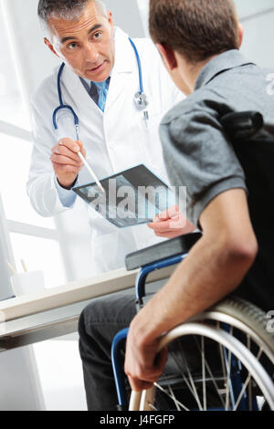 Junger Mann im Rollstuhl treffen Orthopäden. Sie suchen im Röntgenbild und Beratung über Heilung. Stockfoto