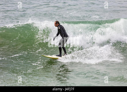 Surfer auf einer Welle genießen die Brandung an einem schönen sonnigen Tag am Strand von Bournemouth auf Feiertag Montag im Mai - Bournemouth, Dorset, England, Großbritannien Stockfoto