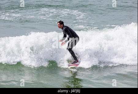 Surfer auf einer Welle genießen die Brandung an einem schönen sonnigen Tag am Strand von Bournemouth auf Feiertag Montag im Mai - Bournemouth, Dorset, England, Großbritannien Stockfoto