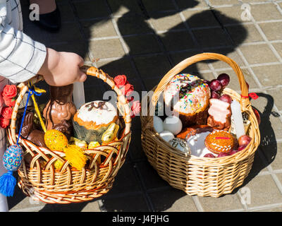 Ein kleines Mädchen hält einen Stock Korb gefüllt mit Ostern angeboten von Eiern und Kuchen, das Russisch-orthodoxe Osterfest zu feiern. Stockfoto