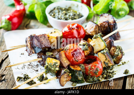 Gegrilltes Gemüse und Rindfleisch Shish Kabobs am Spieß mit Pesto auf rustikalen Holztisch Stockfoto