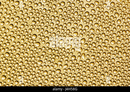 Wassertropfen auf einem hellen goldenen Oberfläche. Stockfoto