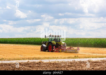 Landwirtschaft - grünen Traktor Pflügen am Feld an einem sonnigen Tag. Stockfoto