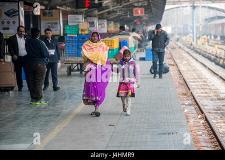 Eine Mutter und Tochter gehen auf einem Bahnsteig an einem Bahnhof in New Delhi, Indien. Stockfoto