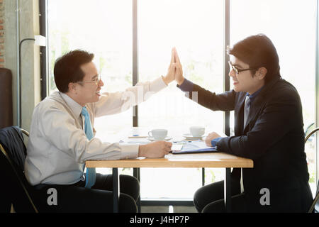 Zwei asiatische glücklich Geschäftsmann geben hohe fünf im Café. Erfolg und Winning Team Geschäftskonzept. Stockfoto