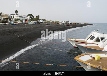 Boote in einem Meer sind mit Seil am Ufer gebunden. Ein Blick auf viele Boote an Land, auf einer Wiese in der Nähe von vulkanischen Sand und welliges Meer auf die Insel Stromboli in Italien. Stockfoto